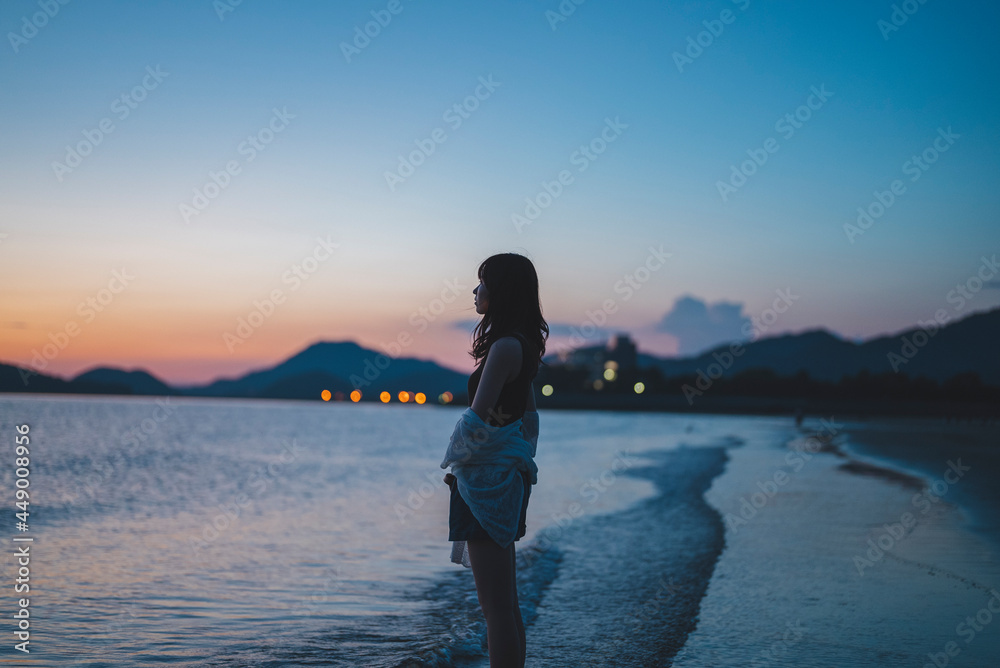 Fototapeta premium 夕暮れの海にいる女性