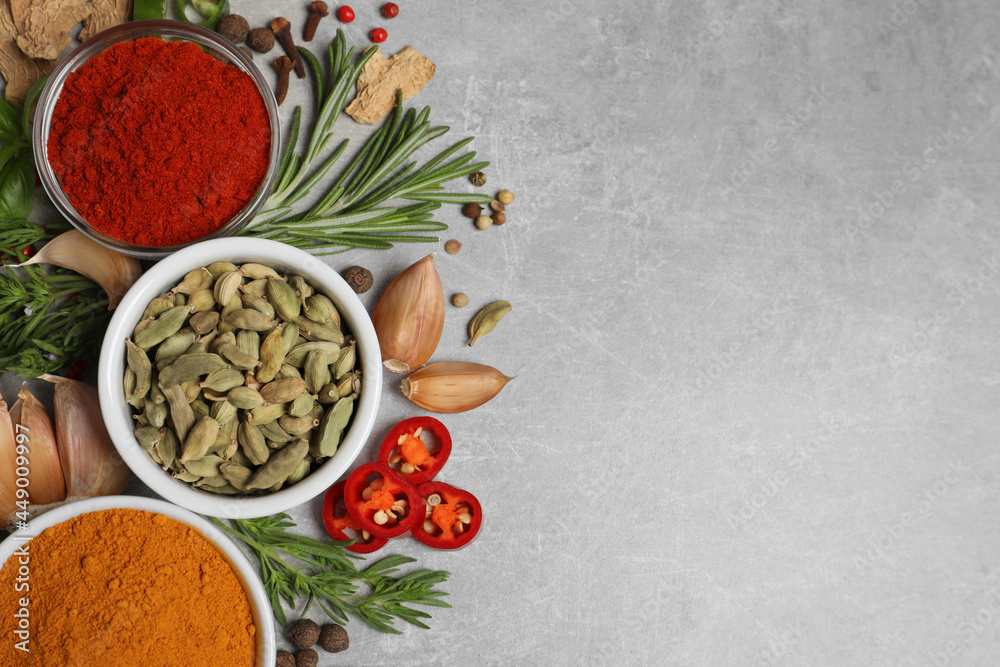 Flat lay composition with different natural spices and herbs on light grey table, space for text
