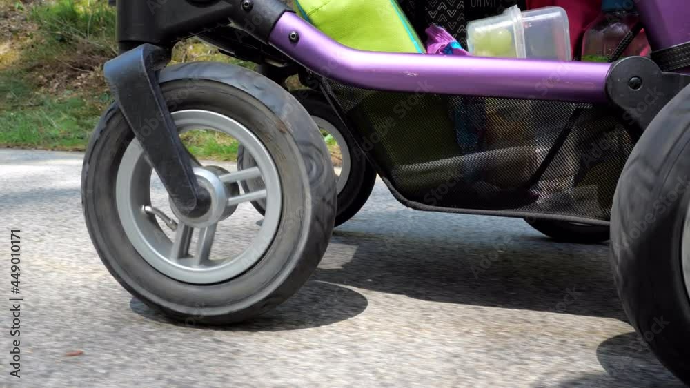 Detailed front wheel of baby stroller during walking at park Detailed front wheel of baby stroller during walking at park