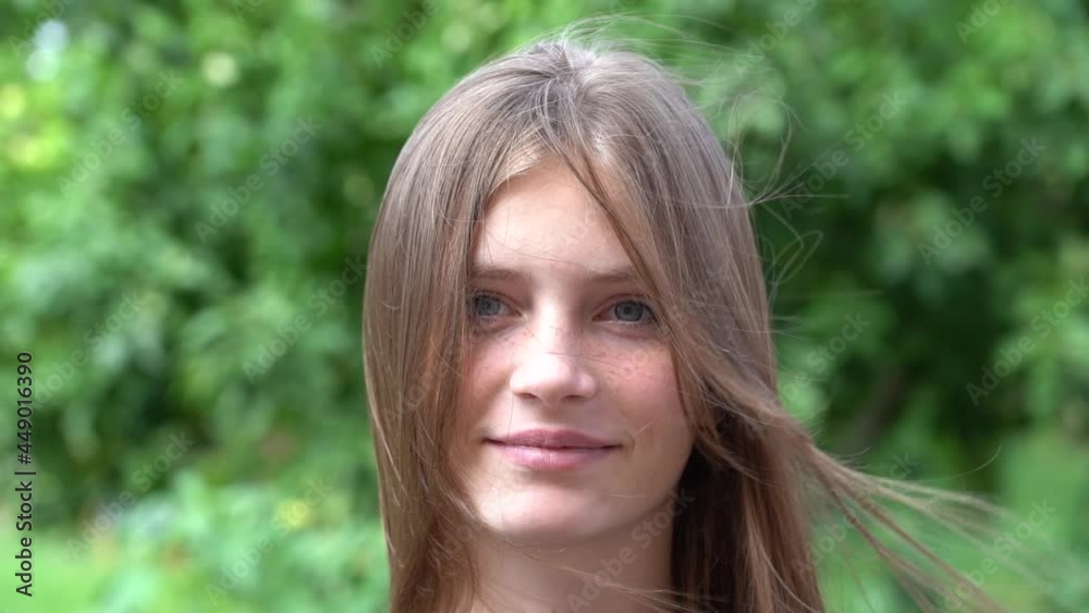 Beautiful happy young girl in nature. Close up portrait outdoors, slow motion Beautiful happy young girl in nature. Close up portrait outdoors, slow motion