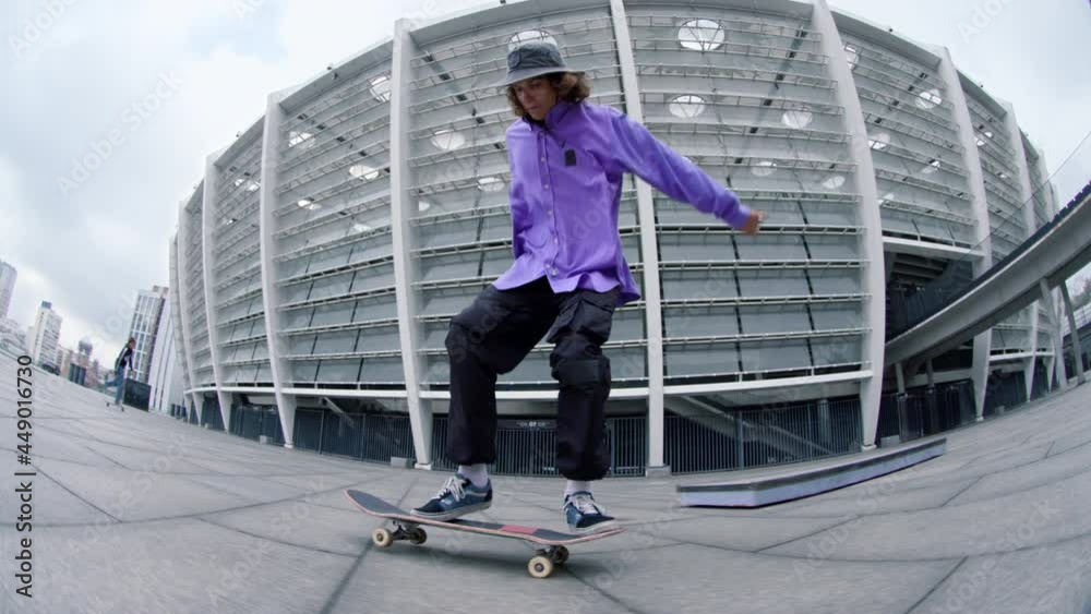 Sporty man making kickflip outdoor. Active hipster riding skateboard outside.