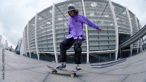 Sporty man making kickflip outdoor. Active hipster riding skateboard outside.