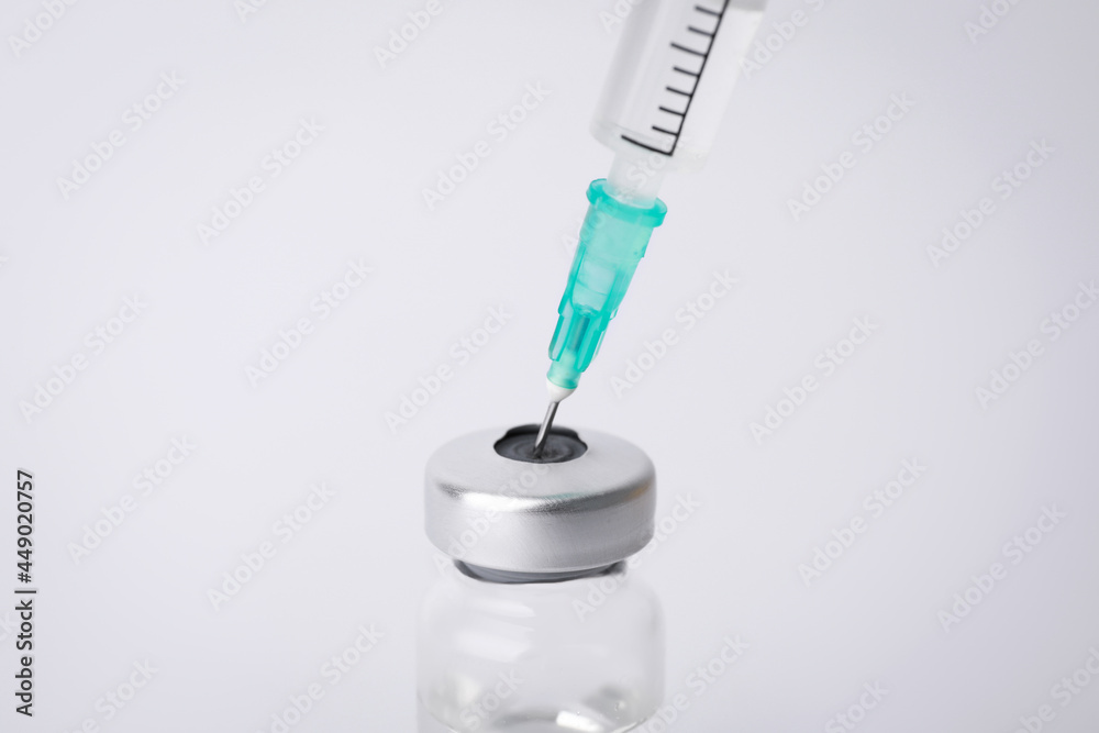 Filling disposable syringe with medicine from vial on white background, closeup Filling disposable syringe with medicine from vial on white background, closeup
