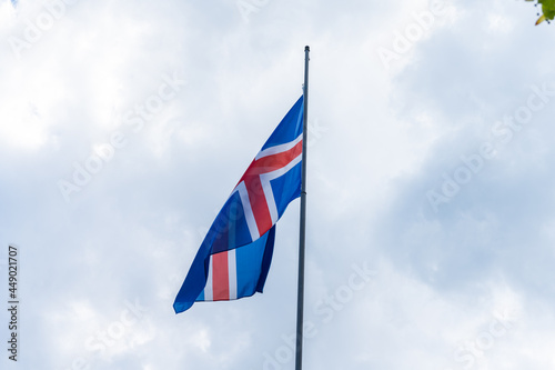 Fotografie The red, blue and white Icelandic flag waving in the wind