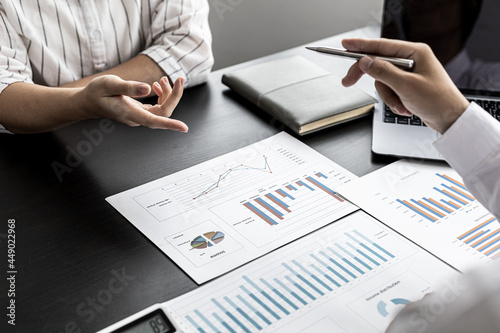 A businessman holding a pen and pointing to a businesswoman, he is explaining the problem of falling sales to business partners in detail to make a decision. Company management concept.