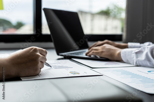 Close-up businesswoman holding a pen pointing to a bar graph document of company financial data, she is reviewing the company's monthly financial documents. Finance concepts and money management.