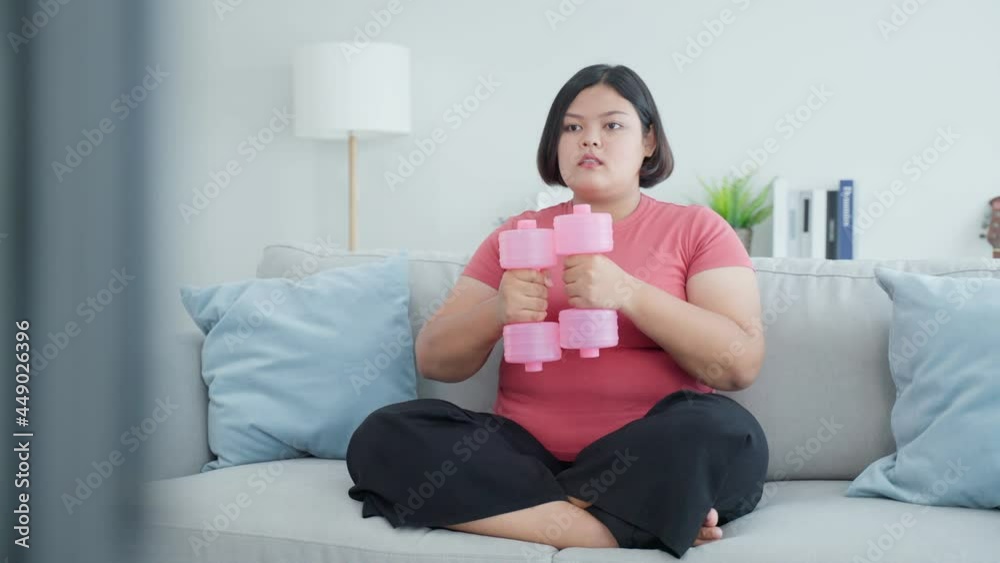 Asian young plus size girl use dumbbell workout in living room at home Asian young plus size girl use dumbbell workout in living room at home