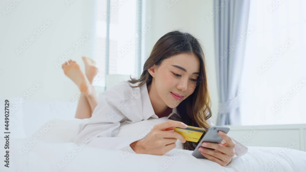 Asian attractive woman enjoy shopping online on bed at home in morning Asian attractive woman enjoy shopping online on bed at home in morning