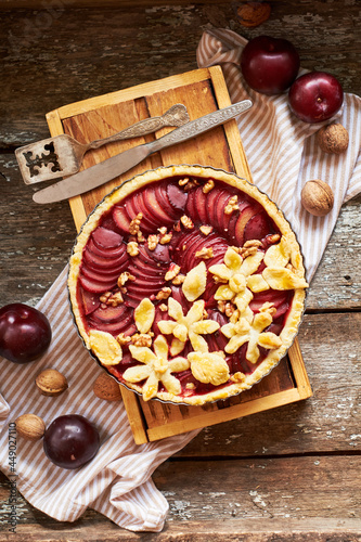 Pie with plum and nuts. Short crust pastry, chopped plums. Top view. Wooden background.