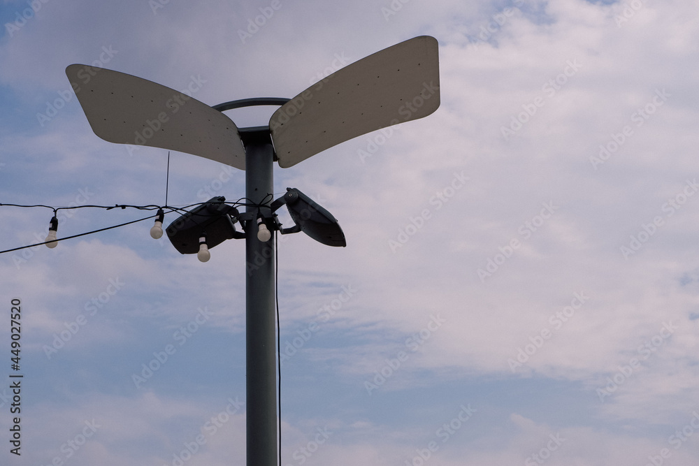 Modern park lighting pole with LED spotlights and reflectors against a blue sky. Modern park lighting pole with LED spotlights and reflectors against a blue sky.
