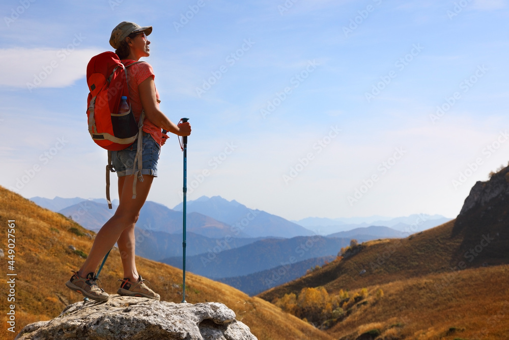Female tourist with backpack admires the beautiful views of the mountains