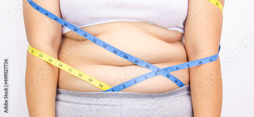 Beautiful fat woman with tape measure She uses her hand to squeeze the excess fat that is isolated on a white background. She wants to lose weight, the concept of surgery and break down fat under the