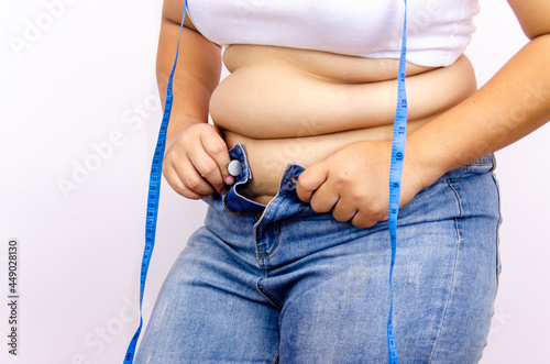 Beautiful fat woman with tape measure She uses her hand to squeeze the excess fat that is isolated on a white background. She wants to lose weight, the concept of surgery and break down fat under the