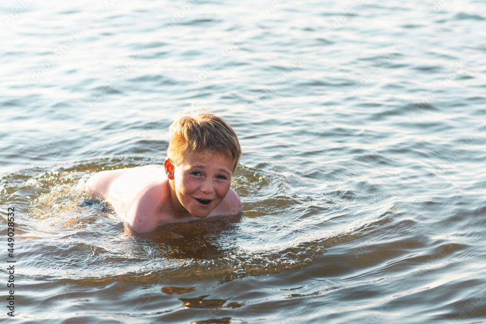 Happy smiling boy having fun swimming in the water.Cute boy swimming in water. Summer vacation.Copy space. Happy smiling boy having fun swimming in the water.Cute boy swimming in water. Summer vacation.Copy space.