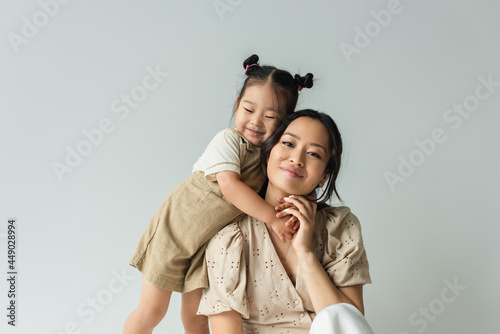 Canvastavla cheerful asian toddler daughter hugging happy mother isolated on gray