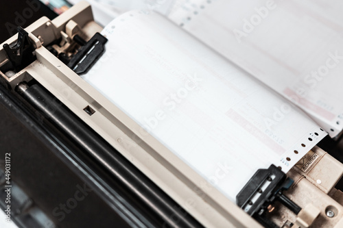 Close up of continuous paper being feed into old dot matrix printer. Dot matrix printer can print multiple (copy) of document or receipt at once. photo
