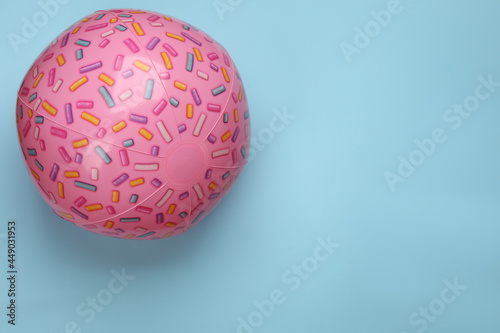 Pink beach ball on light blue background, top view. Space for text