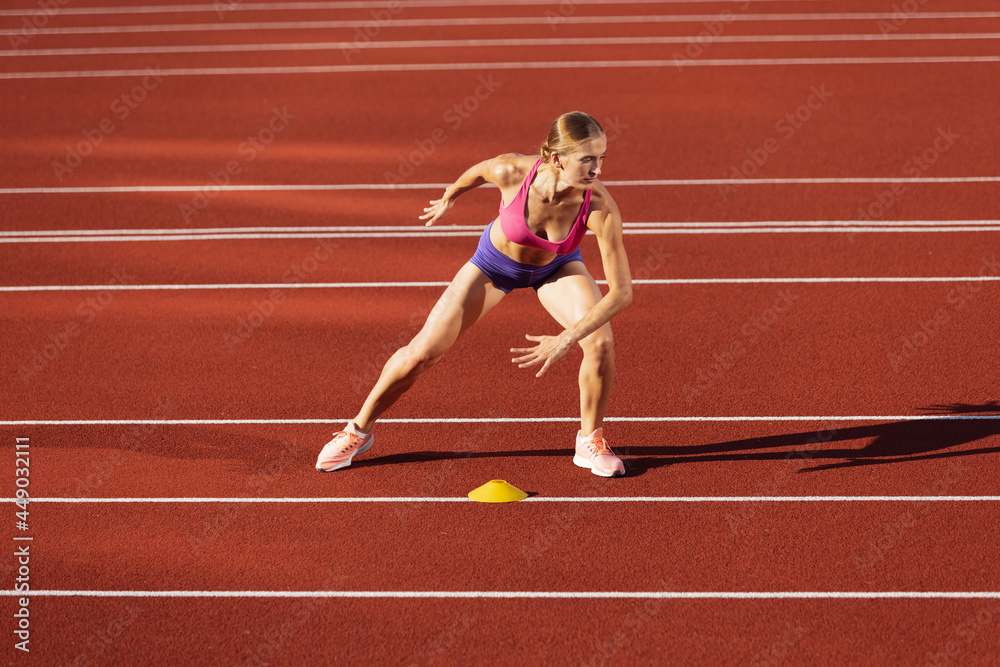 One Caucasian woman, female athlete, runner practicing alone at public stadium, sport court or running track outdoors. Summer sport games.