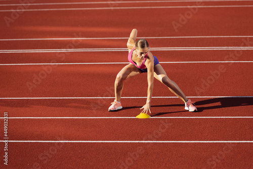 One Caucasian woman, female athlete, runner practicing alone at public stadium, sport court or running track outdoors. Summer sport games.