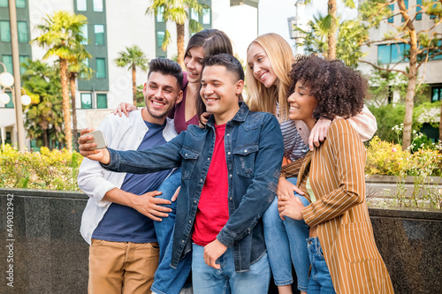 Group of five happy multicultural friends taking a selfie