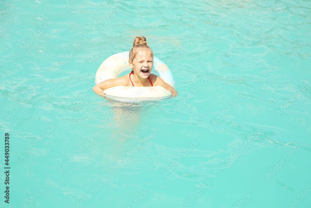 beautiful happy blonde girl swims in the pool with a round lifebuoy