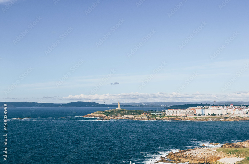 Blue view of the sea side in A Coruña with lighthouse in center