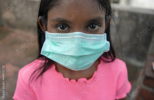 Young tensed brunette girl staring into the camera wearing a medical mask outdoors | protection against virus outbreaks and respiratory diseases | healthcare concept