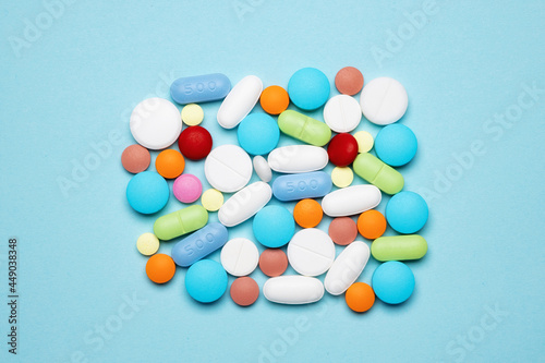 A group of different tablets close-up on a light blue background. The concept of medicine, treatment with pills and antibiotics for various diseases. 
