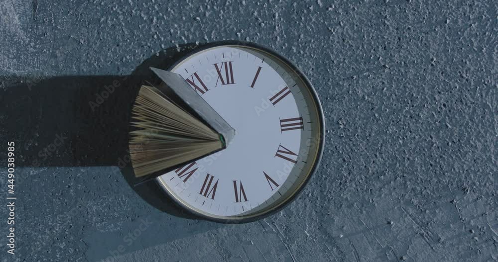 4K Book's pages turning by wind on 24 hours antique clock with classic roman numerals . Wind browse pages of old historic book . Mystical , abstract and symbolically video. Shot on ARRI Alexa camera .