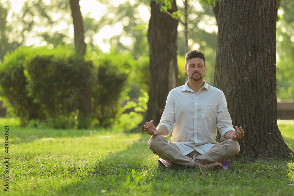 Man meditating in park on sunny summer day. Space for text Man meditating in park on sunny summer day. Space for text