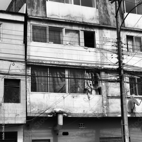 Very old apartments with windows with drying cloths and poles of lights and wires (in black and white)