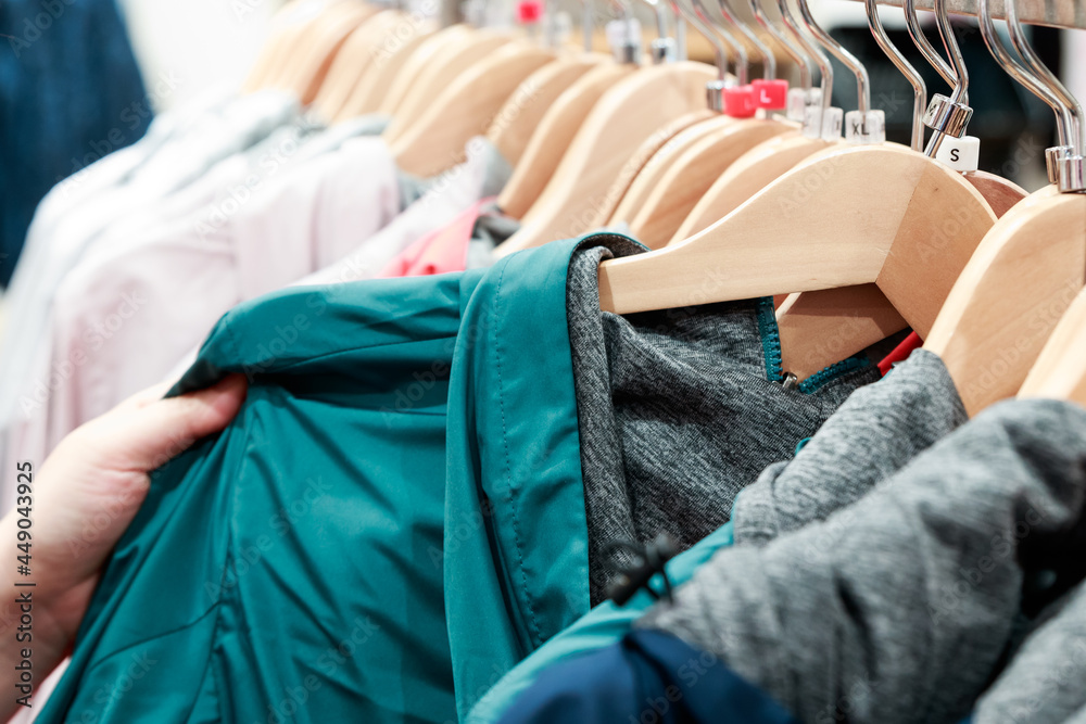 Φωτογραφία Close up of woman hand searching through bunch of colorful clothes and shirt on