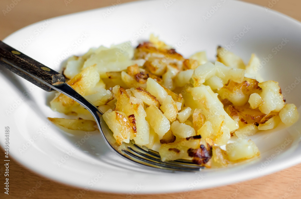Delicious home-fried potatoes on a plate with a fork. Ready portion.