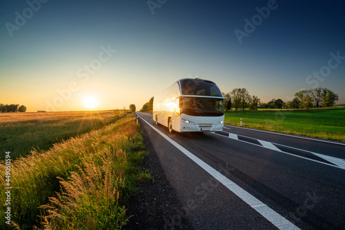 Obraz na płótnie White bus traveling on the asphalt road in rural landscape at sunset w salonie