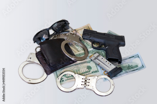 Gun and money. Crime, mafia, killer and violence concept. Semi-Automatic handgun firearm with mags and rounds, leather wallet in a pile of dollar bills with handcuffs and sunglasses. The black handgun