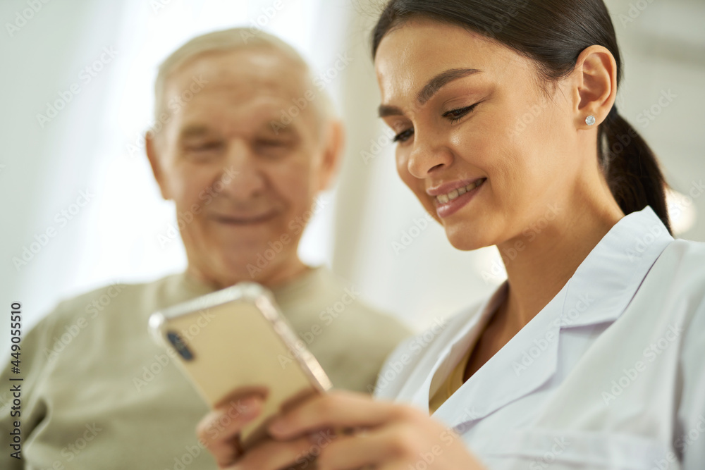 Smiling nurse and senior citizen looking at smartphone screen Smiling nurse and senior citizen looking at smartphone screen