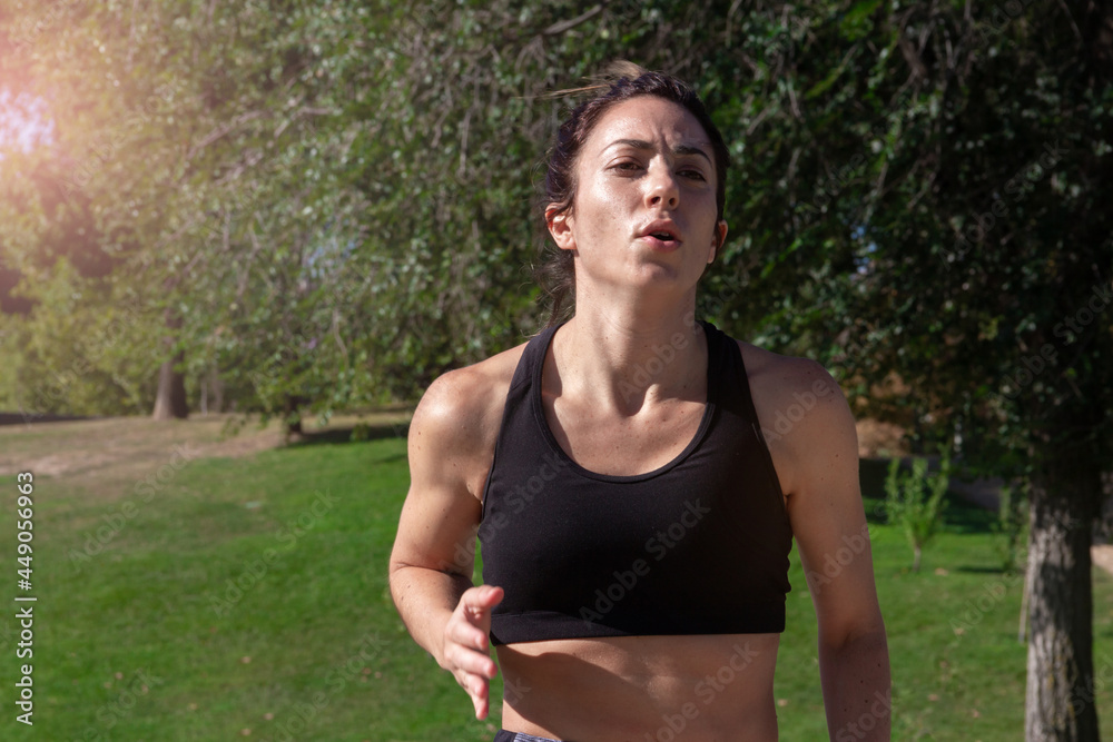 Young woman running through a park on a sunny day. Healthy lifestyle. Selective focus. Young woman running through a park on a sunny day. Healthy lifestyle. Selective focus.