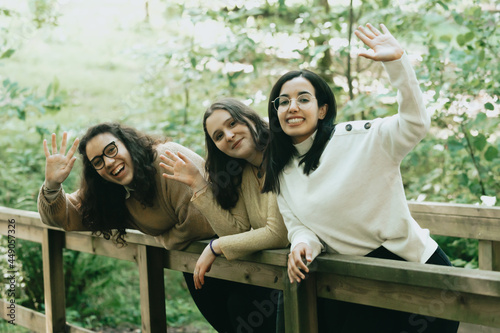 Three young woman saluting to the camera effusively while smiling, friendship and happiness concept photo