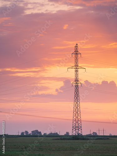 high voltage tower on field with beautiful sunset sly behind with copy space