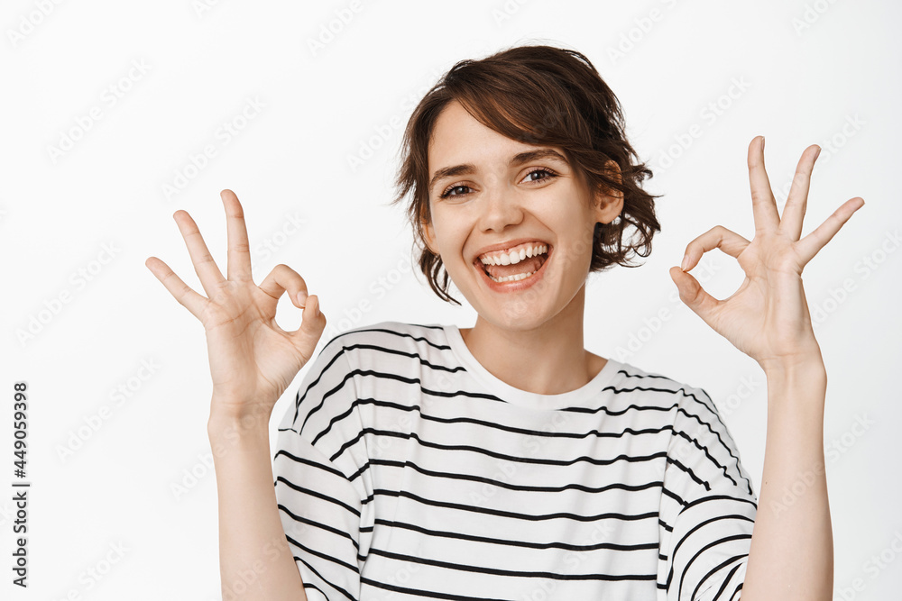 Wow really not bad, good choice. Impressed good-looking modern 20s woman in yellow sweater, nod acceptingly, squinting show okay, approval sign, stand white background Wow really not bad, good choice. Impressed good-looking modern 20s woman in yellow sweater, nod acceptingly, squinting show okay, approval sign, stand white background