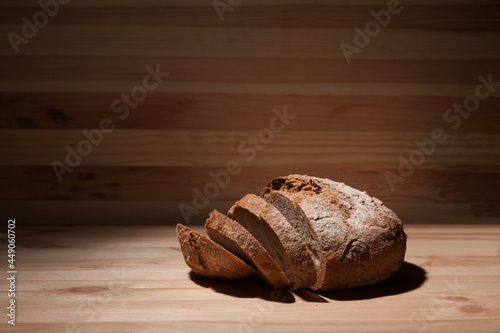 Fresh handmade wheat bread cut into pieces on wooden background in the contrast light. horizontal frame side view with space area for text or design