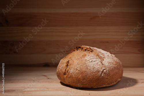 Handmade fresh wheat bread on wooden background in the contrast light. horizontal frame side view with space area for text or design