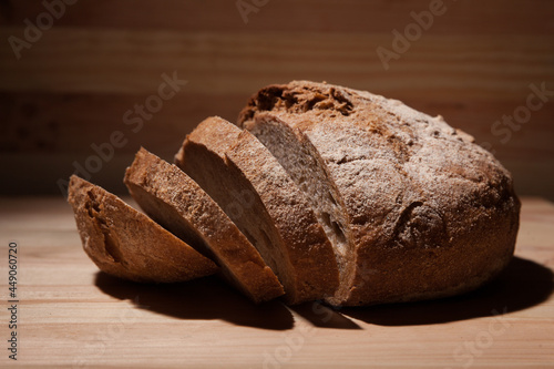 Fresh handmade wheat bread cut into pieces on wooden background in the contrast light. horizontal close-up frame side view