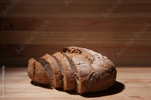 Fresh handmade wheat bread cut into pieces on wooden background in the contrast light. horizontal frame side view with space area for text or design