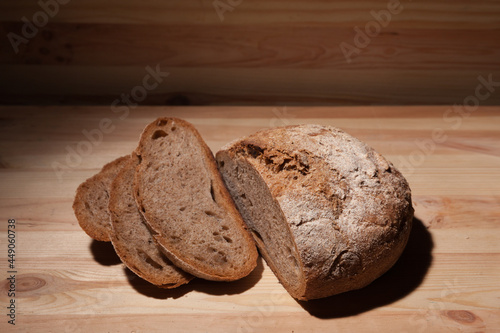 Fresh handmade wheat bread cut into pieces on wooden background in the contrast light. horizontal frame high angle view