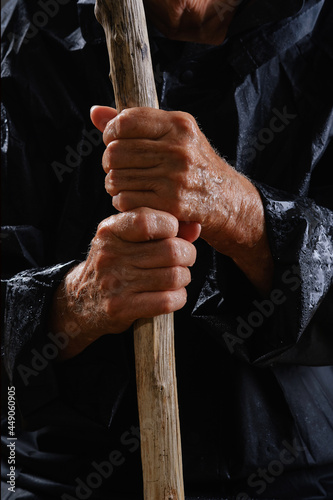 Close up of wet hands elderly woman holding walking stick. Raindrops on hands. Selective focus on hands wrinkled skin. © VLADISLAV