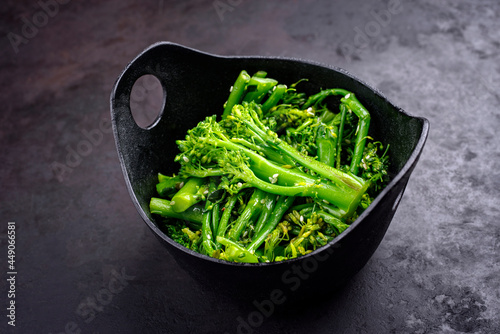 Fresh rapini broccoli rabe with sesame as top view on a black bowl with copy space photo