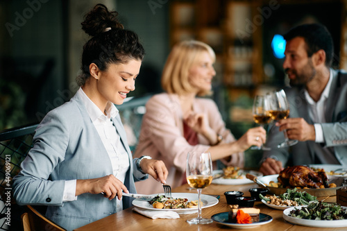 Happy businesswoman enjoys in lunch with co-workers in restaurant.