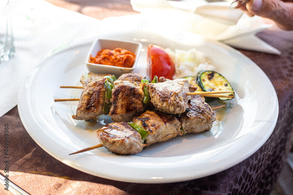 Barbecue skewers with juicy meat and sauce on plate, closeup. Grilled meat and vegetables.