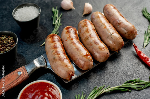 grilled sausages, on a meat knife on a stone background